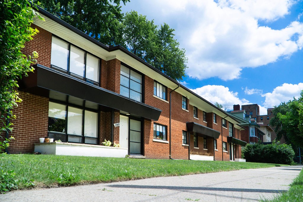 A row of red brick houses with white windows and black shutters.