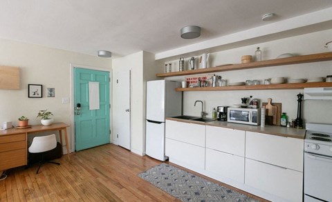 A kitchen with white cabinets and a green door.