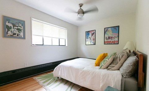 A bedroom with a bed, pillows, and pictures on the wall.