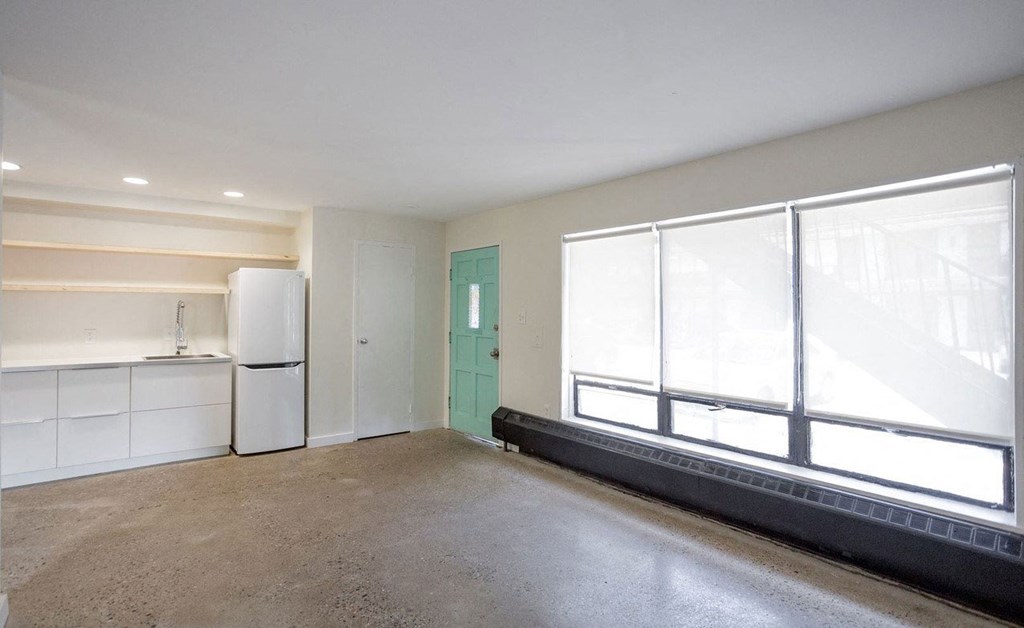 A room with a green door and a white fridge.