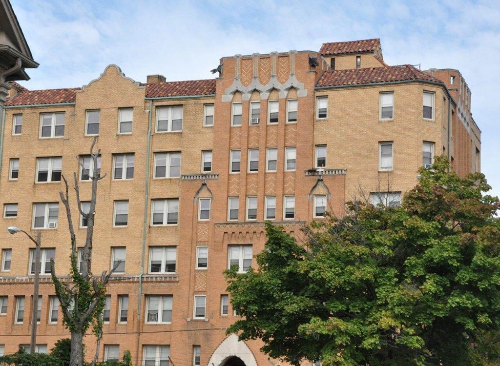 A large brick building with a tree in front.