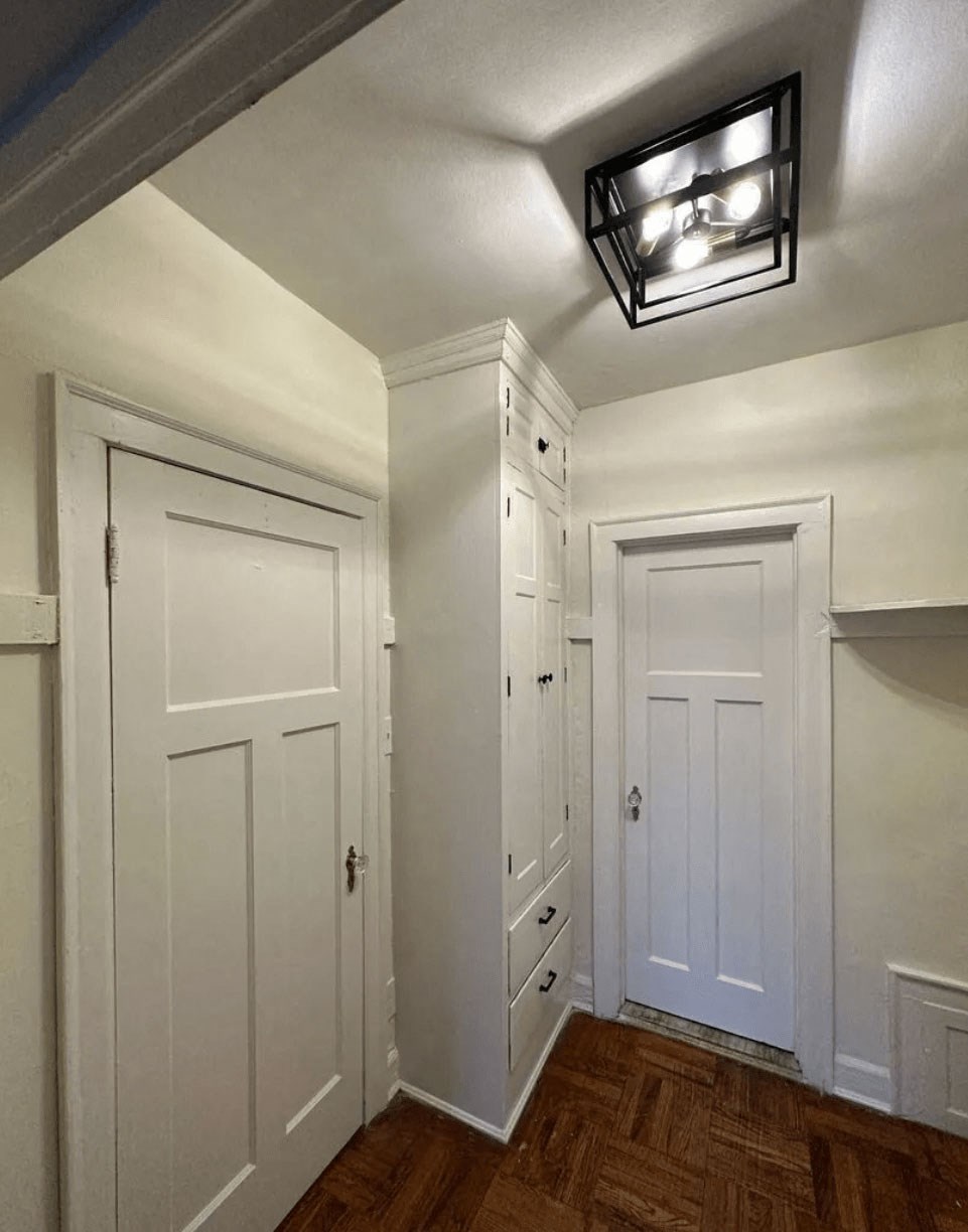 A hallway with white doors and a light on the ceiling.