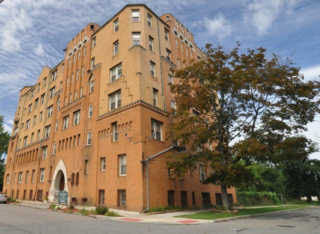 A large red brick building with a tree in front.