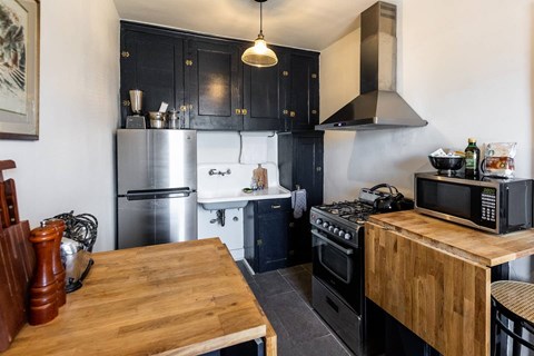 A kitchen with a wooden table and black cabinets.