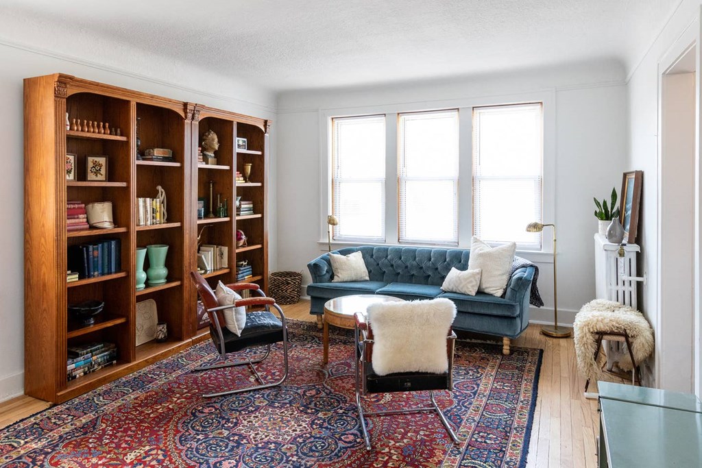 A living room with a blue couch, a rug, and a bookshelf.
