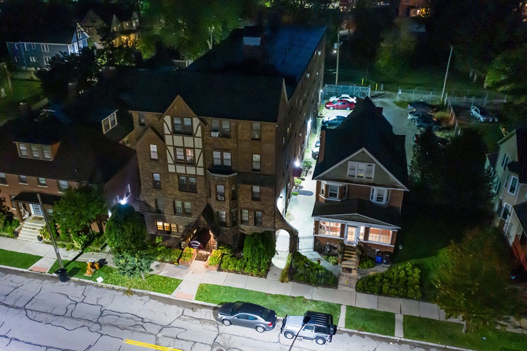 A nighttime street view of a residential area with cars parked on the side of the road.