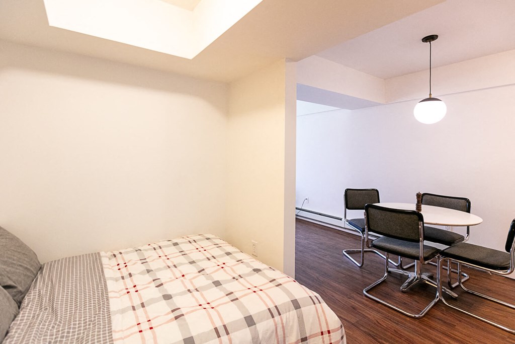 A bedroom with a bed and a table with chairs.