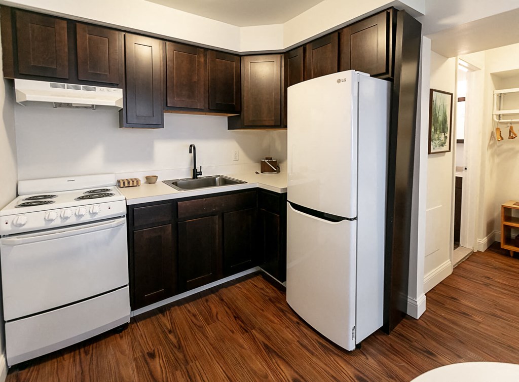A kitchen with white appliances and dark wood cabinets.