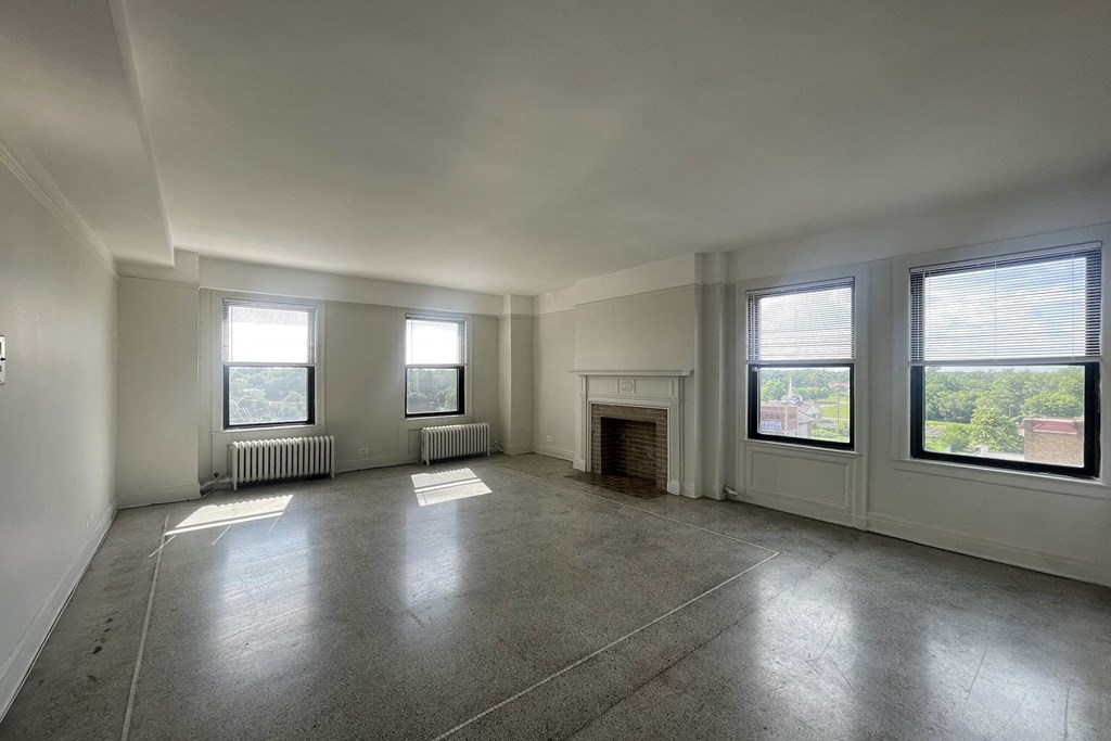 A large empty room with a fireplace and windows.