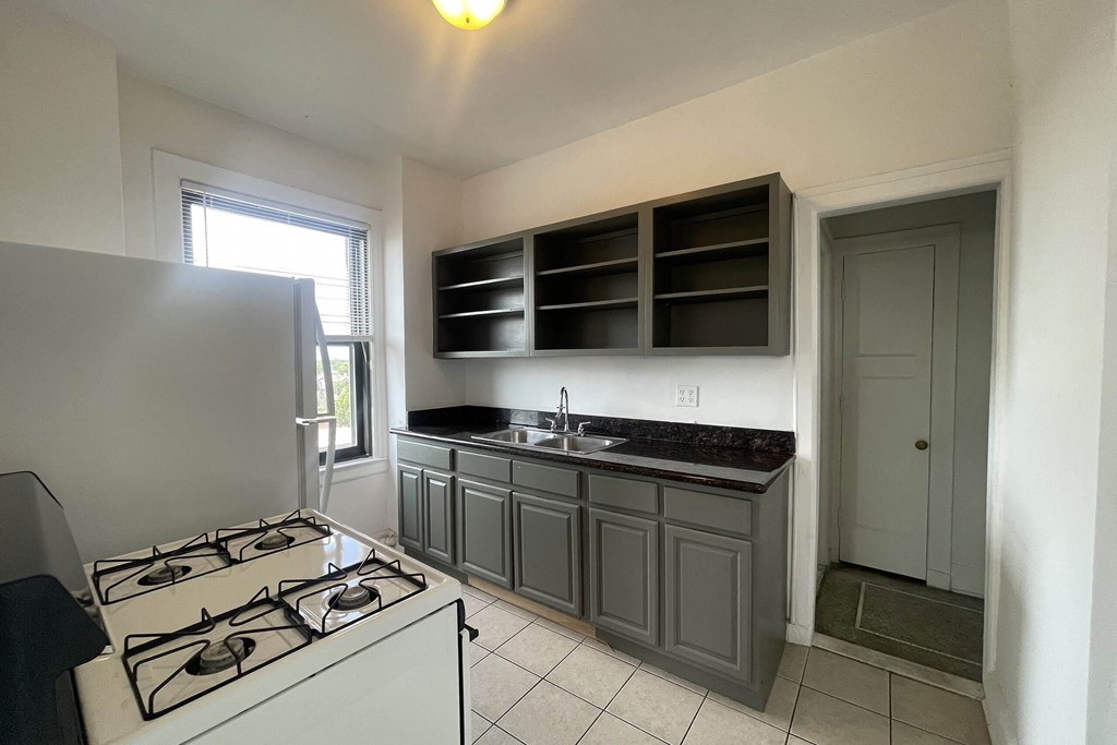 A kitchen with a white stove top oven and a sink.
