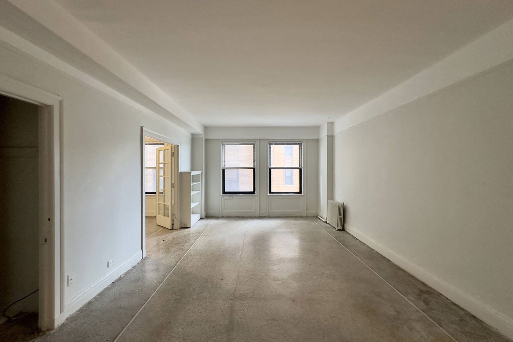 A large empty room with a door on the left and a window on the right.