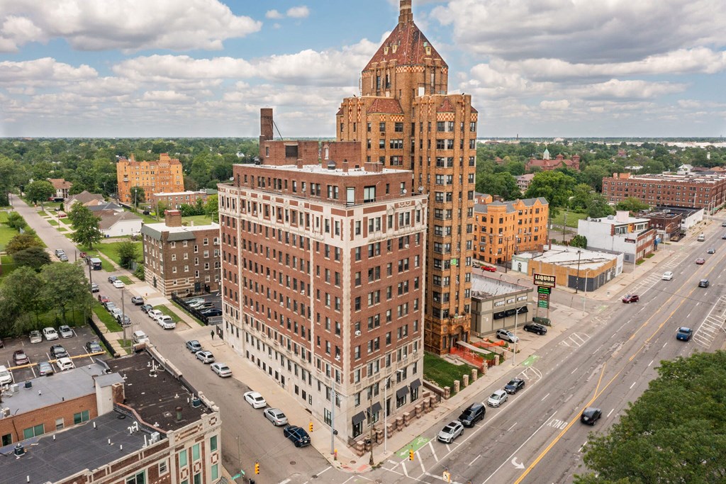 A large red brick building with a tower sits in the middle of a busy intersection.