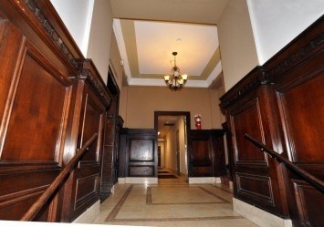 A hallway with wood paneling and a chandelier.