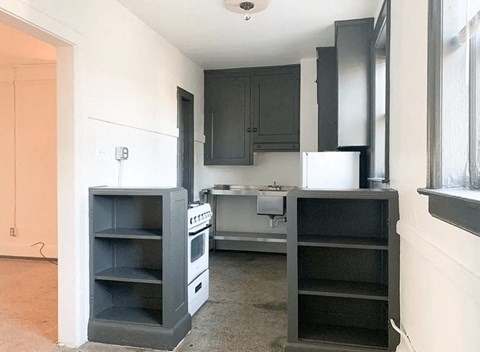 A kitchen with a white refrigerator, black cabinets, and a white stove top oven.