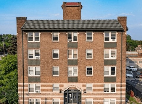 A tall brick building with a black door and windows.
