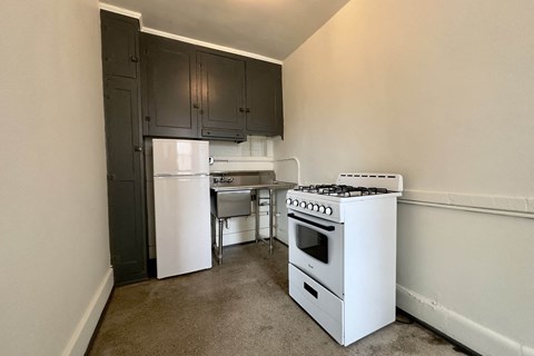 A kitchen with a white stove and black cabinets.