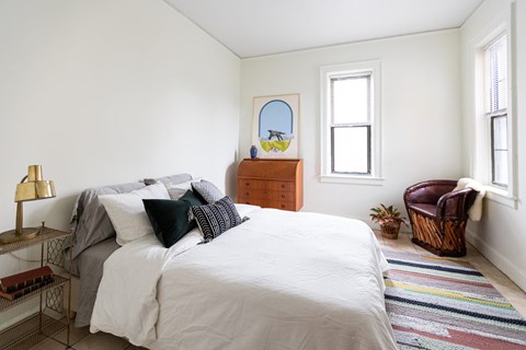 A bedroom with a large bed and a chair.