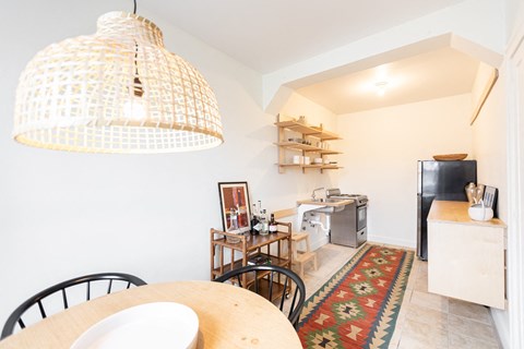 A kitchen with a table and chairs under a hanging light fixture.