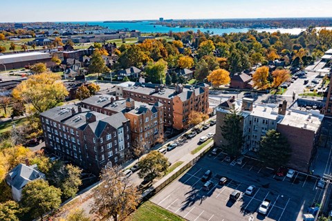 A view of a city with a parking lot in the foreground and a large building in the middle.
