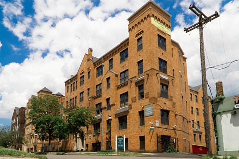 A large red brick building with a green sign on the front.