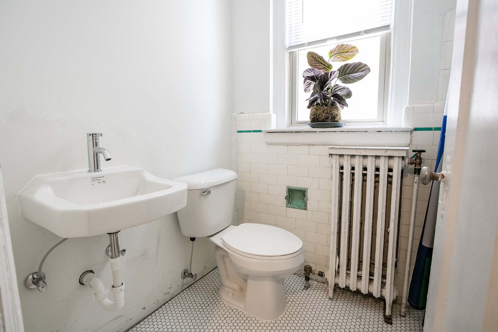 A white sink and toilet in a bathroom with a window.