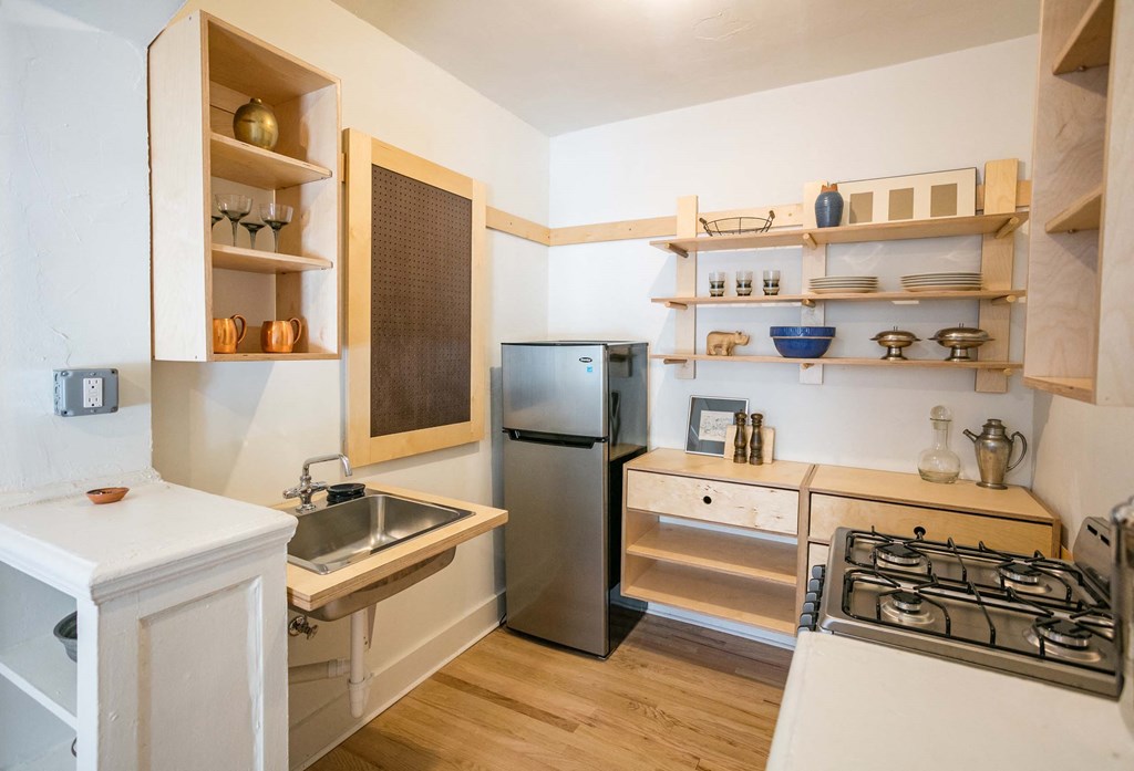 A kitchen with a stainless steel refrigerator, a sink, and a stove top.
