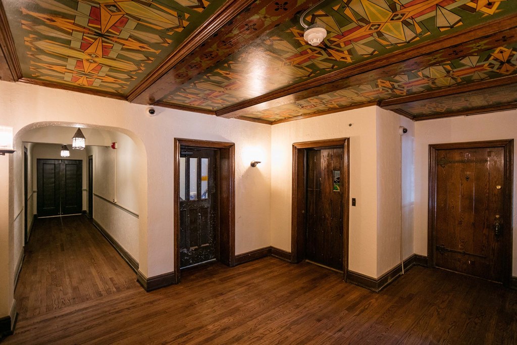 A hallway with wooden floors and a ceiling with a colorful mural.