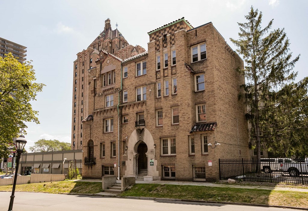 A large brown building with a black fence in front.