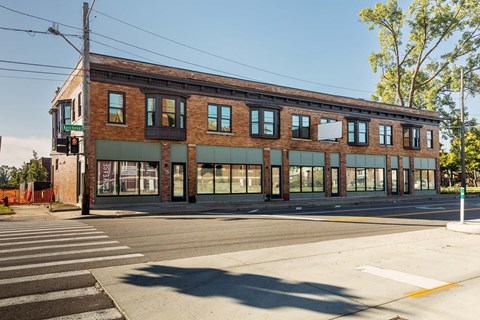 A large brick building with a green awning sits on a street corner.