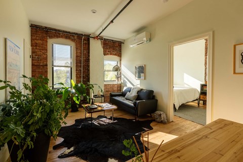 A living room with a black couch and a wooden floor.