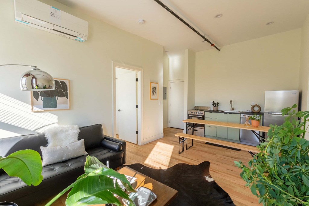 A living room with a black couch and a wooden floor.