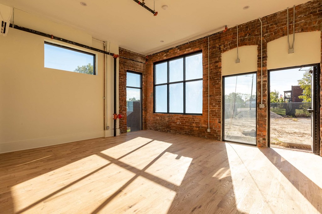 A room with wooden floors and large windows with a view of a construction site outside.