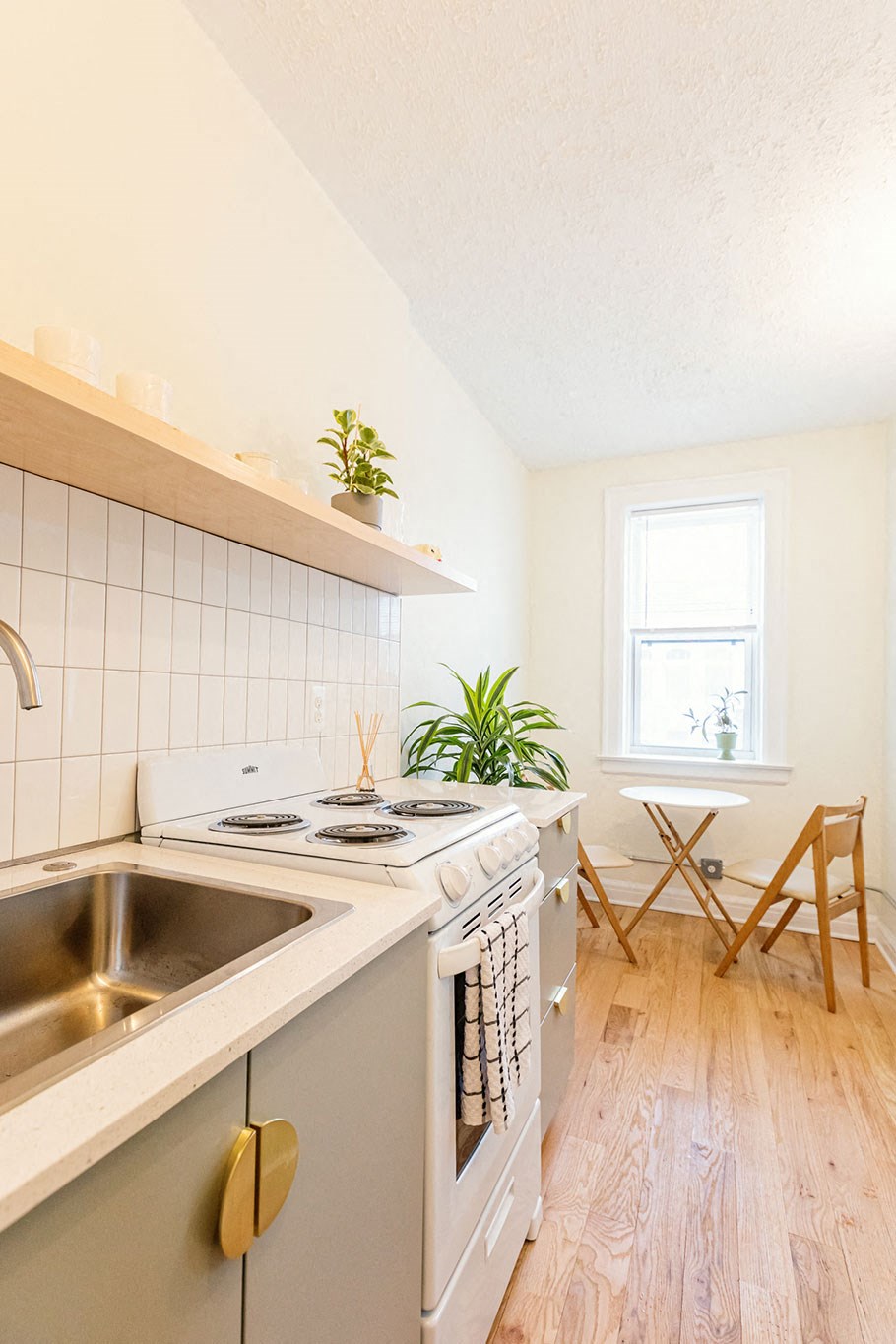 A small kitchen with a stove, sink, and a window.
