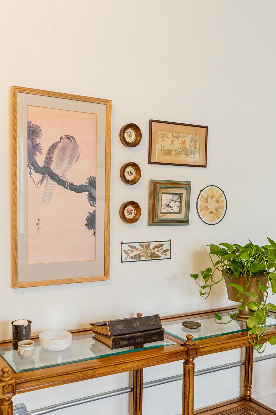 A framed picture of a bird is hanging on a wall above a glass table.
