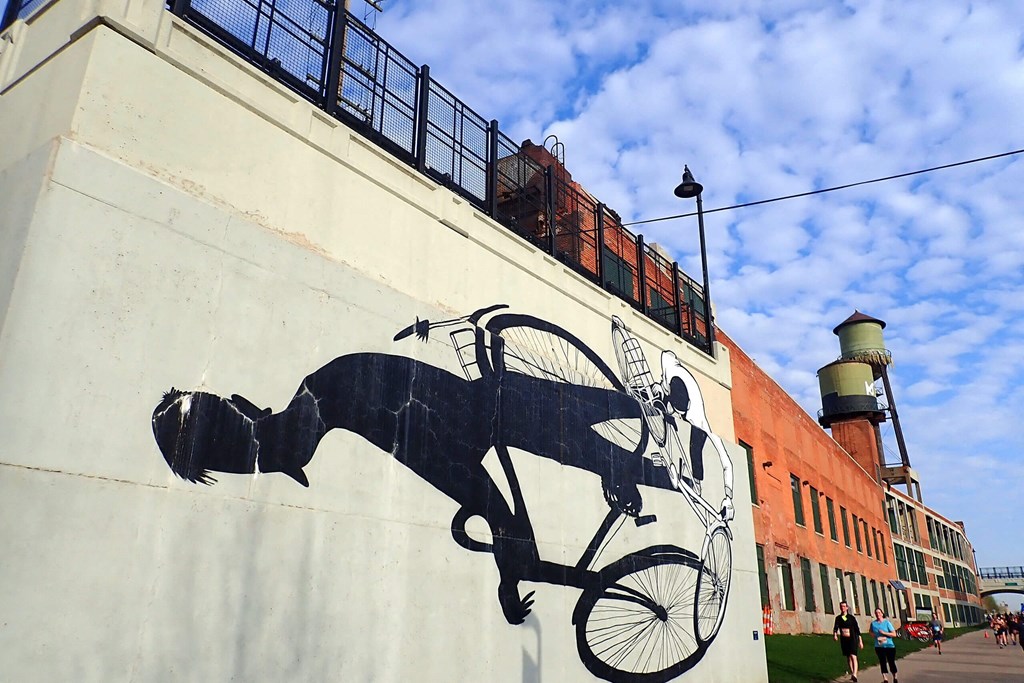 A mural of a man riding a bicycle is painted on a wall.