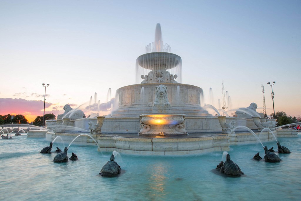 A large fountain with a statue on top is surrounded by water jets.
