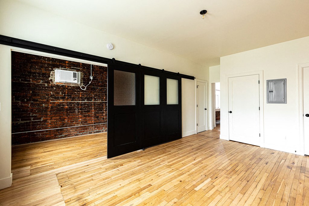A room with wooden floors and a brick wall.