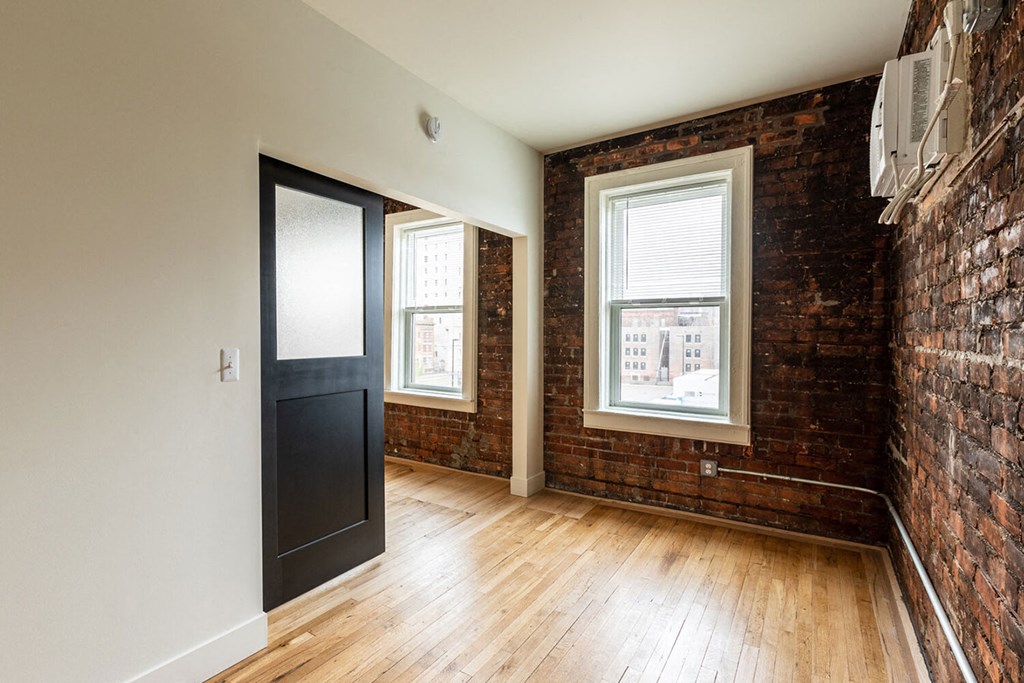 A room with a brick wall and wooden floors.