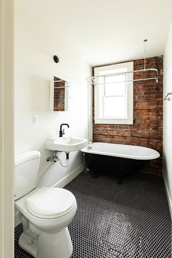 A white toilet sits next to a white sink in a bathroom with a black and white tiled floor.