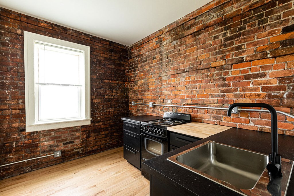 A kitchen with a brick wall and a window.