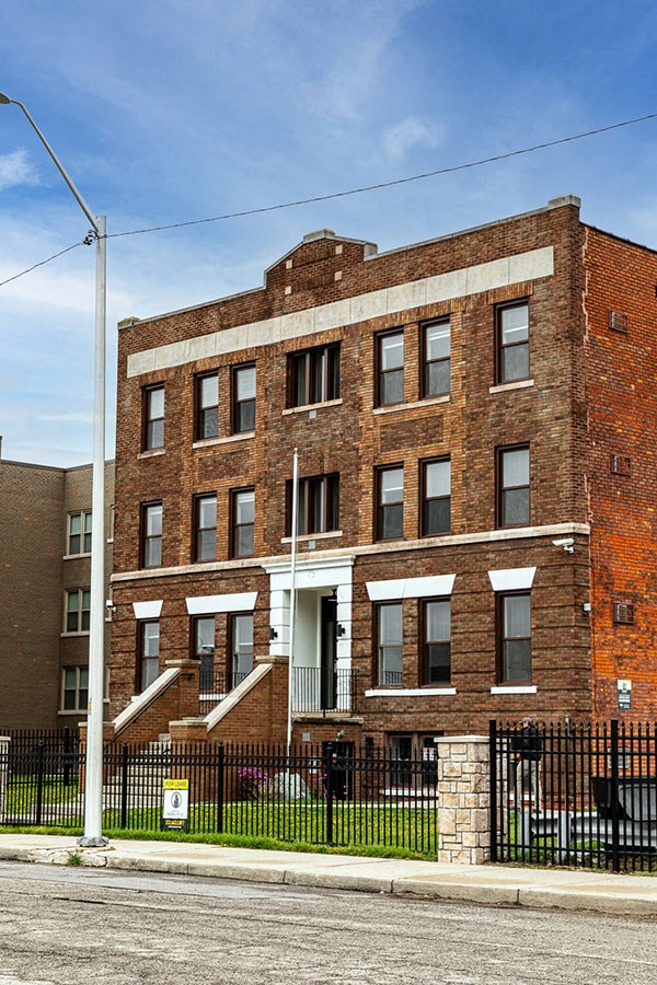 A red brick building with a black fence in front.
