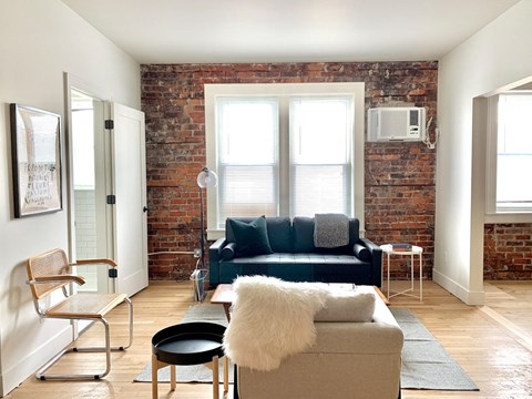 A living room with a blue couch and a white fur throw.