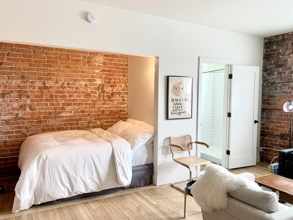 A bedroom with a brick wall and a bed.