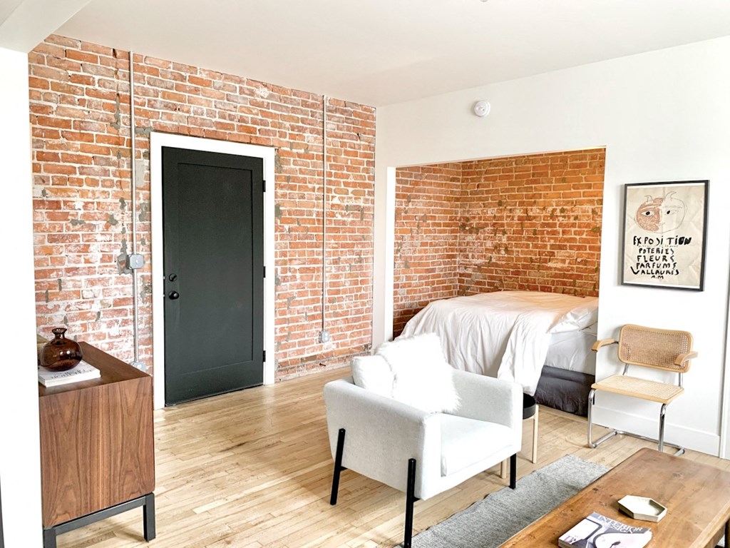 A room with a brick wall and a bed.