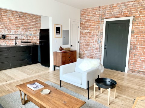 A kitchen with a black fridge and a white chair.