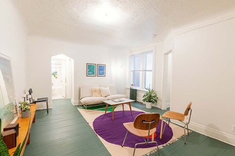 A living room with a purple rug and a brown chair.