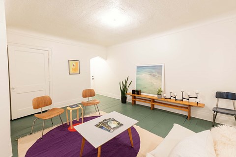 A living room with a white couch and a purple rug.