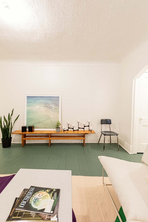 A living room with a white couch, a wooden bench, and a painting on the wall.