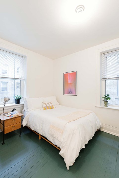 A bedroom with a bed, nightstand, and window.