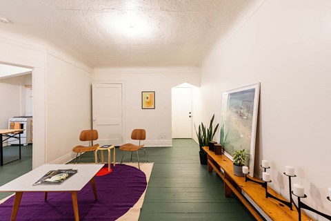 A room with a purple rug and a long wooden bench.